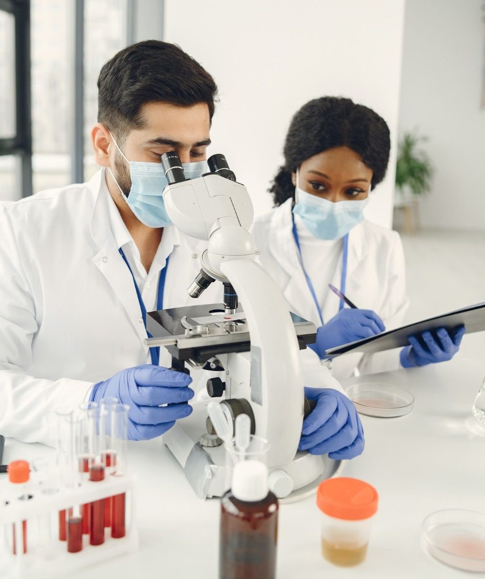 Two laboratory scientists examining samples with a microscope