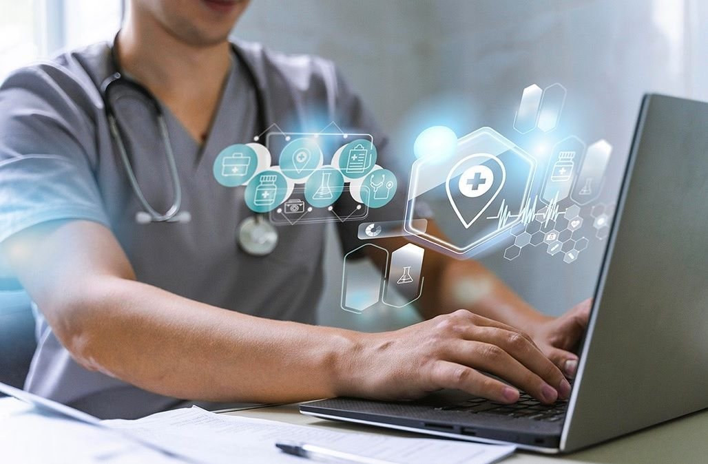 A clinician working on a laptop with digital health icons overlaid