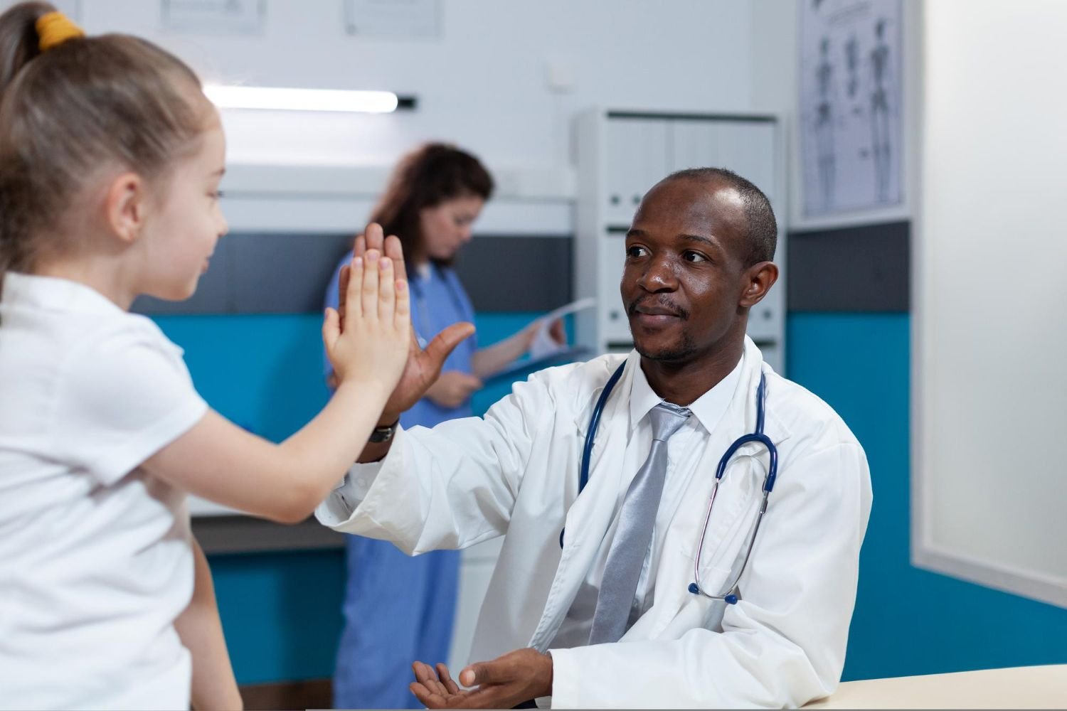 A physician shares a high five with a young patient in a clinic