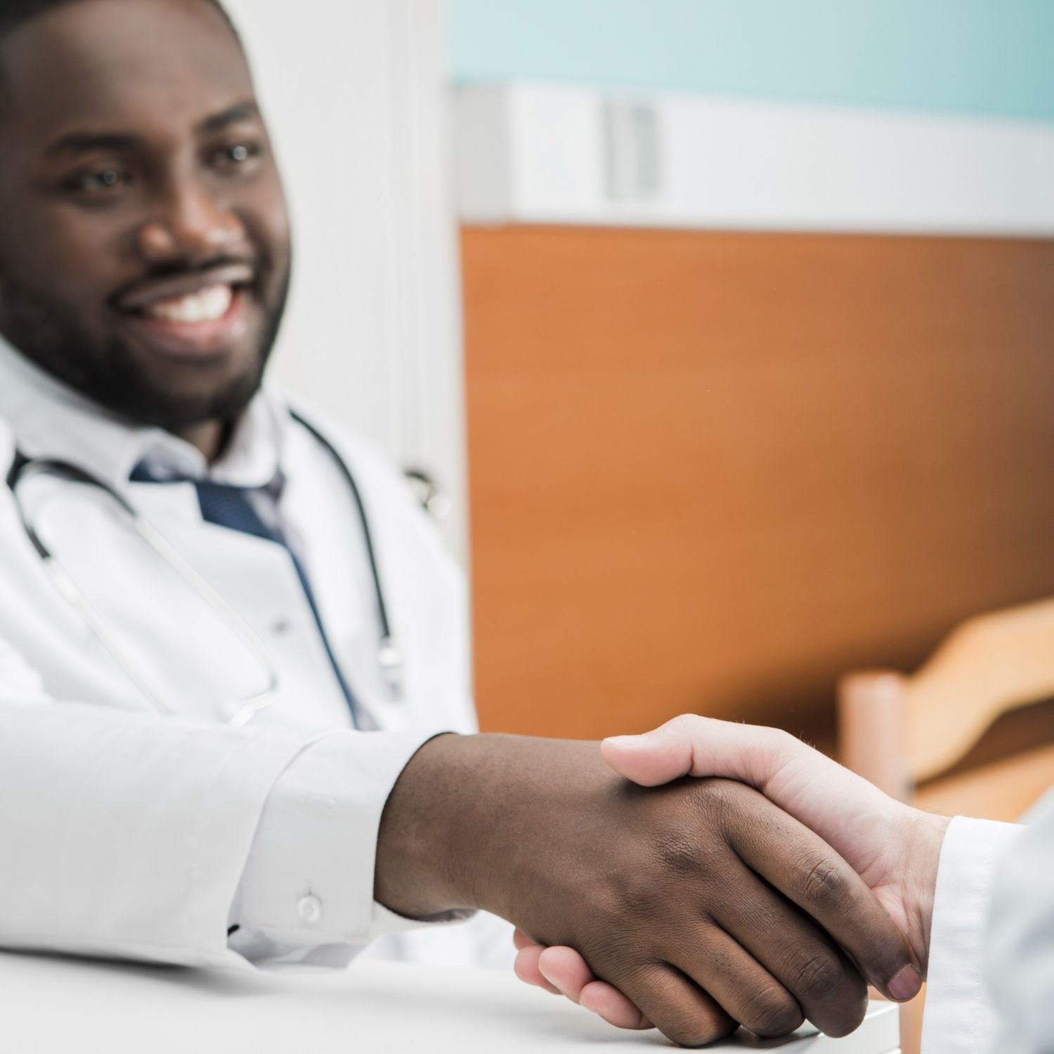 A smiling physician shakes hands across a desk