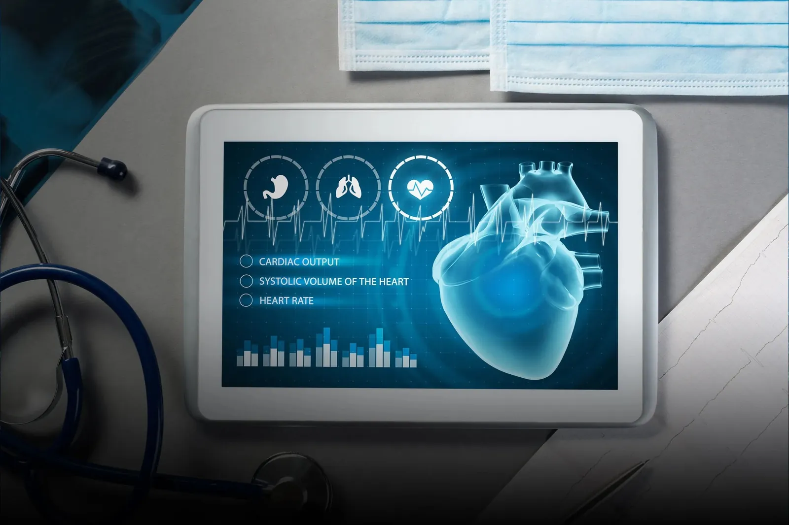 A tablet displays a cardiac health app with a 3D heart model, beside a stethoscope